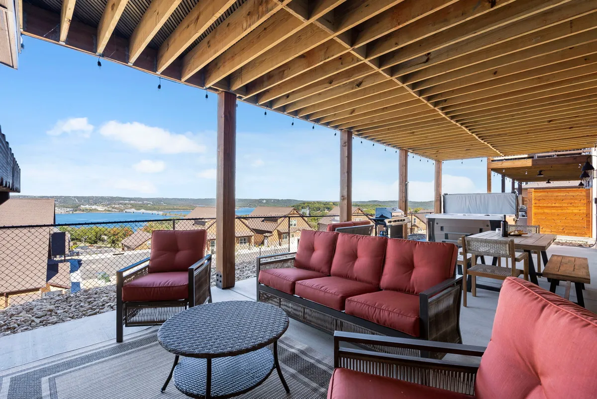 A comfortable outdoor seating area with plush chairs under a wooden ceiling with string lights, overlooking a tranquil water view. The space is ideal for evening gatherings, sunset watching, and casual group entertainment.