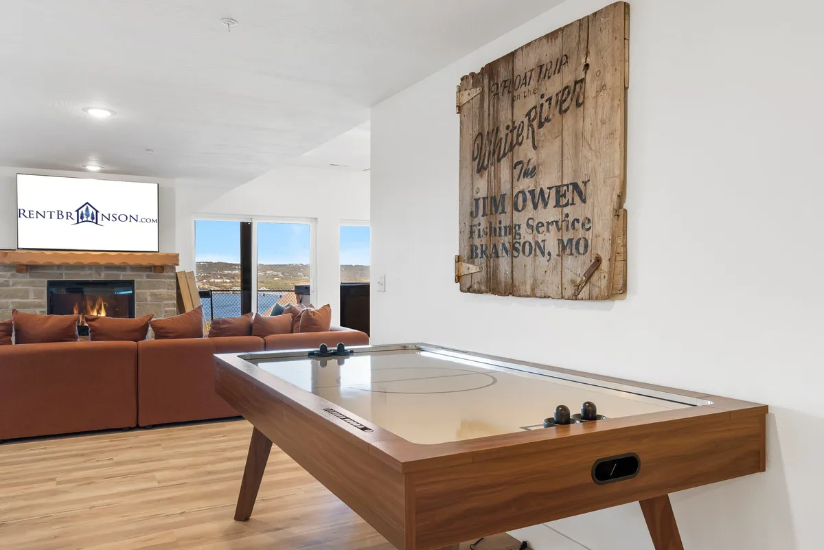 An inviting living area with a central air hockey table, comfortable seating, a television, and wood-accented decor. The atmosphere is cozy and playful, perfect for game nights and relaxed gatherings.
