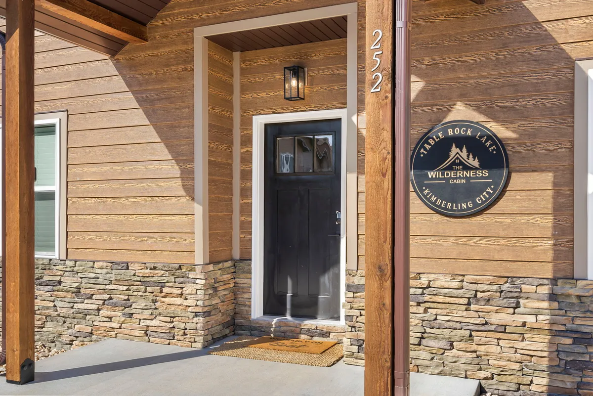 A welcoming exterior entrance to a cabin, with a wooden door, stone wall, and clear signage. The entryway exudes warmth and serves as a literal and figurative gateway to exploring the surrounding area.