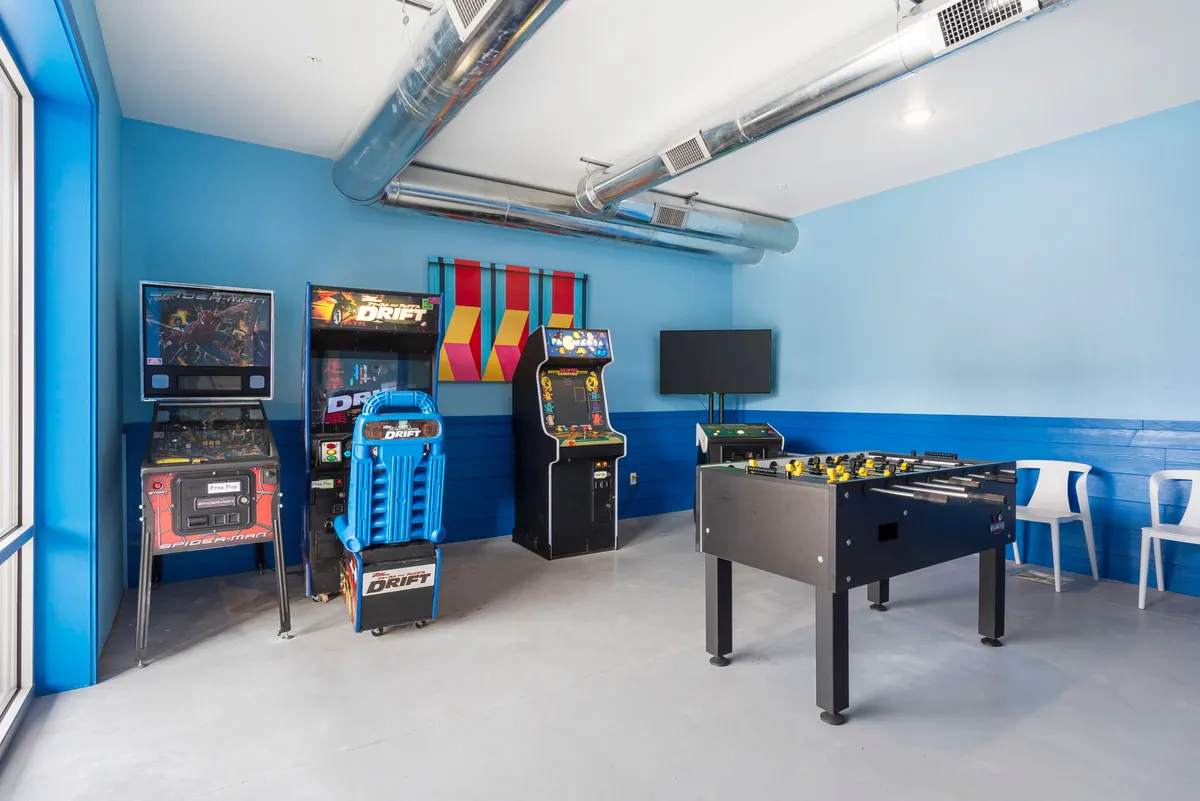 A vibrant game room featuring arcade machines, a foosball table, and lively wall decor. The space is designed for energetic group play and socializing, capturing the thrill of friendly competition.